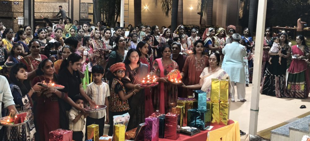 Women and children performing aarti with diyas at a Y.Y.P garba event